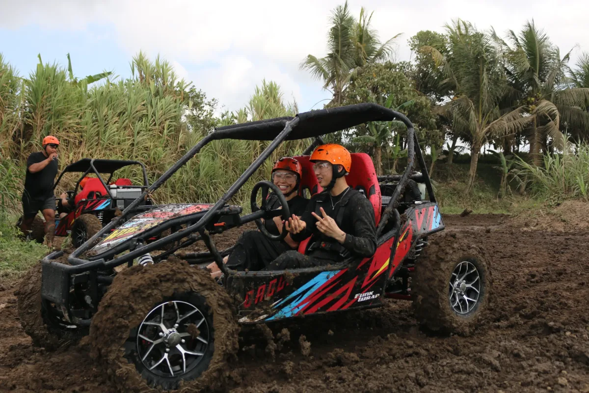 Two riders wearing helmets in a red off-road buggy