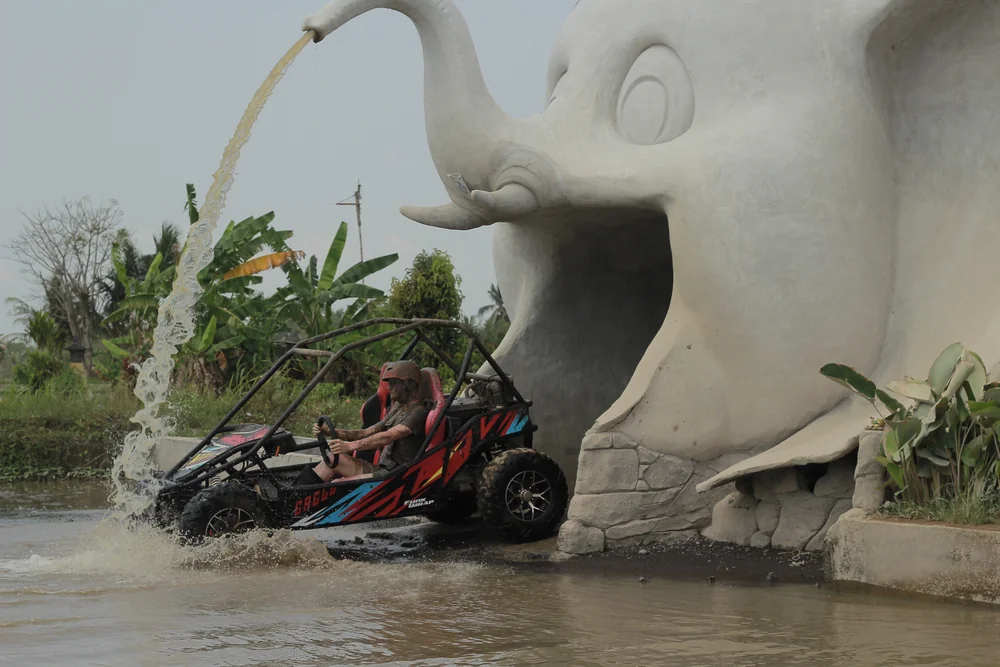 Buggy emerging from the giant elephant cave landmark with water fountain spraying
