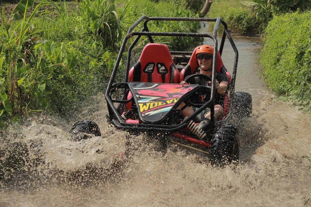 Buggy charging head-on through river water, sending up a dramatic spray