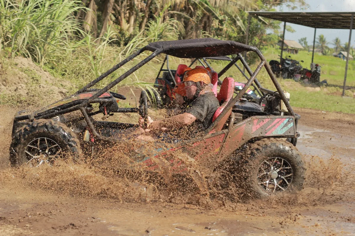 Buggy throwing mud through a wet track